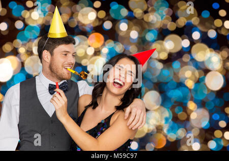 Coppia felice con party soffianti divertendosi Foto Stock