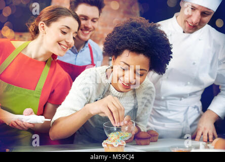 Happy amici e chef di cucina la cottura in cucina Foto Stock