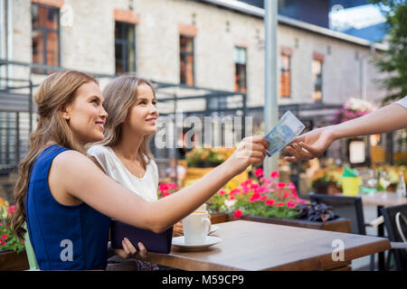Le giovani donne di pagare per il caffè a street cafe Foto Stock