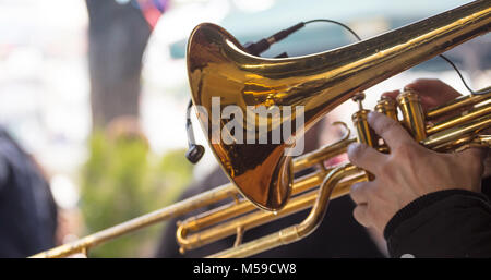 Musicista con tromba in ottone gioca, premendo le valvole con le sue dita, musica classica. Vista ravvicinata con i dettagli, sfondo sfocato. Foto Stock