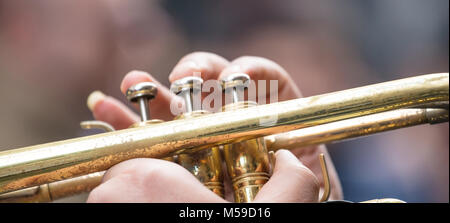 Musicista con tromba in ottone suona musica classica. Le sue dita premere le valvole per dare la migliore qualità del suono. Vista ravvicinata con i dettagli, sfondo sfocato Foto Stock