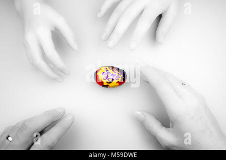 Quattro mani per raggiungere uno Cadbury Creme Egg Foto Stock