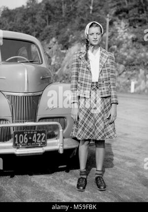 Una giovane donna si distingue per la sua Ford Super Deluxe automobile durante un viaggio su strada, ca. 1942. Foto Stock