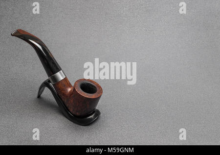 Briar irlandese il fumo di tabacco tubo piegato tipo realizzati di erica su un cavalletto su sfondo grigio Foto Stock