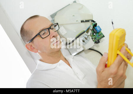 Tecnico senior con multimetro Foto Stock