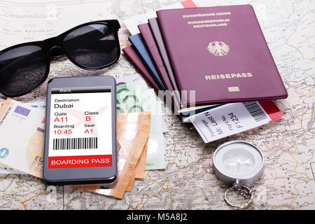 Passaporto e moneta note con lo smartphone che mostra Electric carta di imbarco sulla mappa Foto Stock