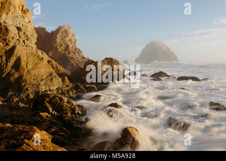 Seascape con le onde che si infrangono sulle rocce al tramonto. Foto Stock