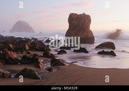 Seascape con le onde che si infrangono sulle rocce sulla spiaggia al tramonto. Foto Stock