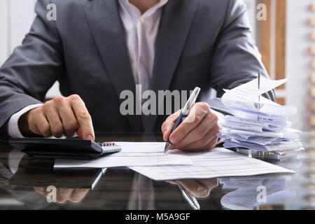 Commercianti la mano della fattura di calcolo con la calcolatrice sulla scrivania Foto Stock