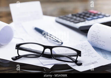 Close-up di occhiali da sole e penna sulla ricevuta Foto Stock