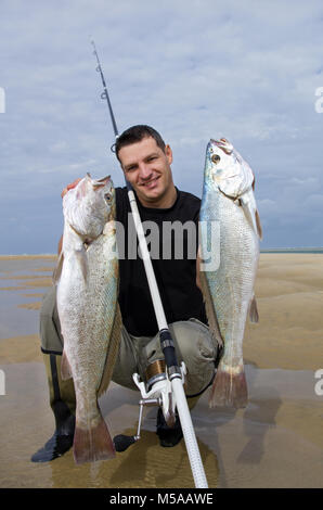 Lucky surf fisherman tenendo un grande pesce di acqua salata Foto Stock