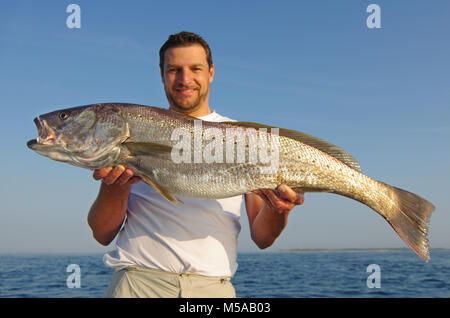 Lucky fisherman tenendo un grande pesce di acqua salata Foto Stock