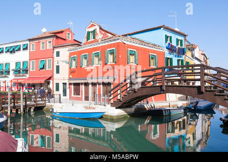 Ponte di legno su fondamenta di Cao Moleca, Isola di Burano, Venezia, Veneto, Italia con riflessioni dei suoi edifici colorati nel canale Foto Stock