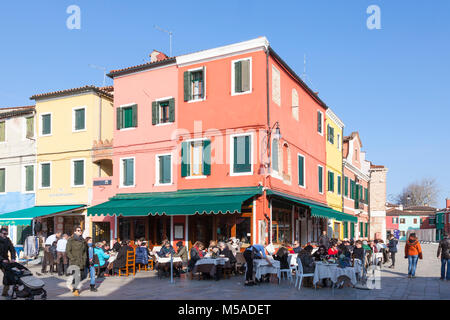 Burano, Venezia, Veneto, Italia. I turisti a pranzare in un ristorante in Via Baldassare Galuppi e Pizza Baldassare Galuppi su una soleggiata giornata invernale sopra il c Foto Stock