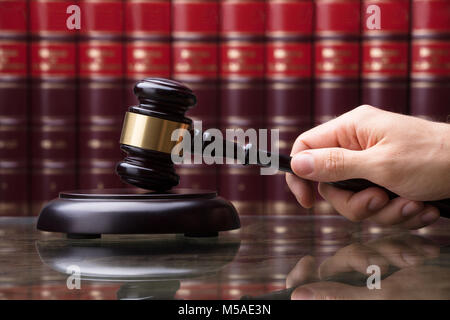 Close-up di mano di una persona che colpisce martello sul blocco di suonare nelle aule di tribunale Foto Stock