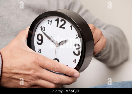 Primo piano di un giovane uomo caucasico regolando il tempo di un orologio Foto Stock