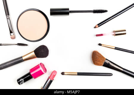 Pennelli per il trucco, matita, rossetto e altri oggetti, formando una cornice su uno sfondo bianco, con copia spazio. Un modello per un trucco artisti della business Foto Stock