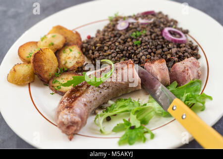 Francia grigliate di Tolosa la salsiccia con insalata e lenticchie e patate Foto Stock