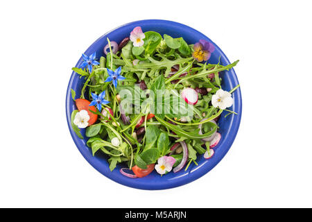 Erba fresca insalata con foglie verdi e i Nasturzi fiori servita in un blu vaso in ceramica su bianco Foto Stock