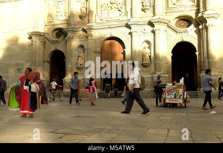 Persone singolarmente rendendo il loro modo attraverso il giorno come i loro sentieri attraversano davanti la mitica cattedrale di Nostra Signora dell'Assunzione a Oaxaca. Foto Stock