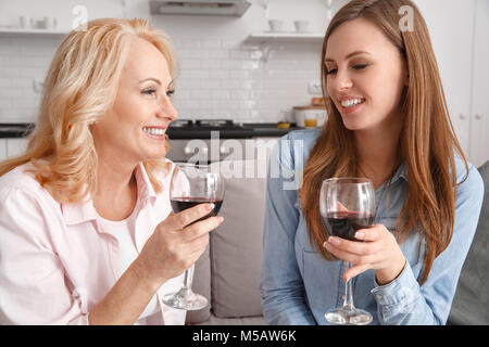 Madre e figlia insieme a casa weekend tenendo i bicchieri di vino rosso Foto Stock