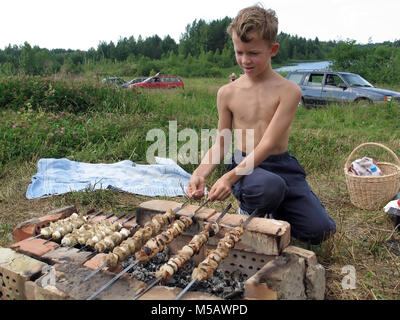 Bambino di otto anni la tostatura carne sul fuoco in campagna Foto Stock