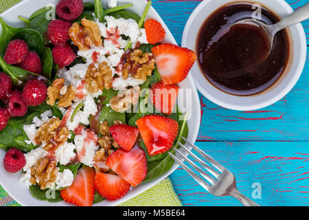 Gustosa insalata fresca con baby spinaci e noci con frutta di rifili di ripe lampone e fragola sul formaggio feta servita con una salsa vinaigrette Foto Stock