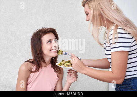 Due donne per alimentare ogni altro in cucina Foto Stock