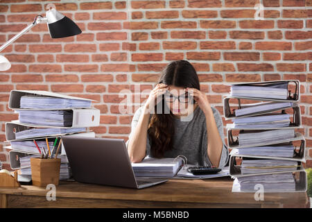 Esaurito imprenditrice lavorando in ufficio con la pila di cartelle sulla Scrivania Foto Stock