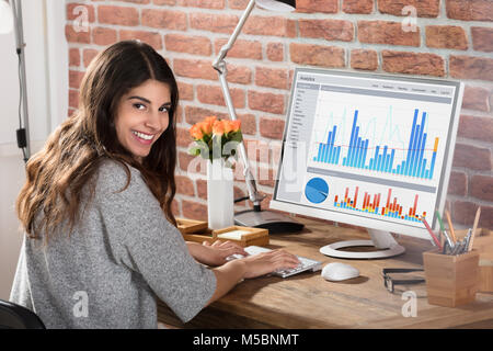 Ritratto di un felice imprenditrice con un grafico sullo schermo del computer Foto Stock
