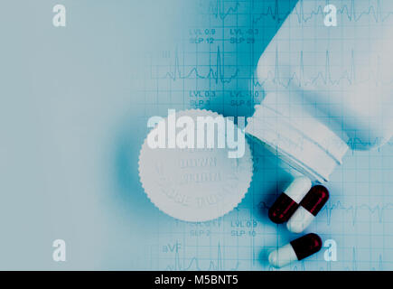 Pillole di capsula e bottiglia aperta e elettrocardiogramma o ECG (elettrocardiogramma) rapporto grafico di carta. EST ( esercizio Stress Test ) risultato. Medicina con prob cardiaco Foto Stock