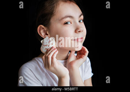 Girl su uno sfondo nero mantiene i serbatoi come orecchini, close-up. Foto Stock