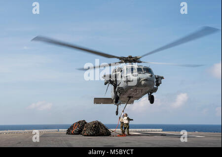 180221-N-NB544-197 sul Mare del Sud della Cina (feb. 21, 2018) Sgt. Kashaun Thompson, da Brooklyn, N.Y., assegnato al 3d Divisione Marine, ganci reti da carico per un MH-60S Sea Hawk, assegnato al 'Sea Cavalieri' di elicottero di mare squadrone di combattimento (HSC) 22, a bordo di un assalto anfibio nave USS Bonhomme Richard (LHD 6) durante un rifornimento in mare con il Henry J. Kaiser-class flotta oliatore di rifornimento USNS Walter S. Diehl (T-AO 193). Bonhomme Richard è operativo nell'Indo-Pacifico regione come parte di un regolarmente programmata di pattugliamento e fornisce una rapida capacità di risposta in caso di un livello regionale di contin Foto Stock