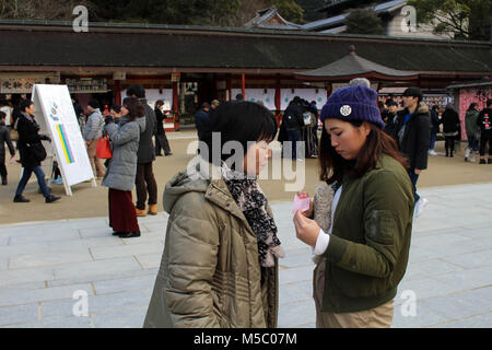 Mamma & figlia controllare il risultato della fortuna-dicono di carta. Prese a Dazaifu Tenmangu, Fukuoka, febbraio 2018. Foto Stock