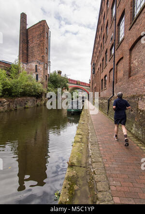 Manchester, Inghilterra, Regno Unito - 2 Agosto 2015: Un pareggiatore corre sulla strada alzaia del Bridgewater Canal accanto a edifici industriali nella zona di Deansgate prossimo Foto Stock