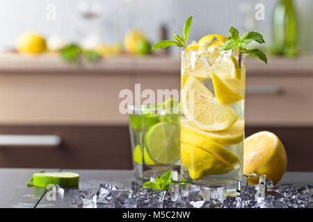 Cocktail con calce , Limone , ghiaccio e foglie di menta piperita su una tavola nera . Foto Stock