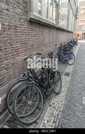 Biciclette messo contro il muro in una stretta viuzza Foto Stock