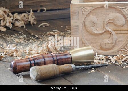 Uno scalpello e un martello vicino a bella scatola di legno con arredamento sul pavimento Foto Stock