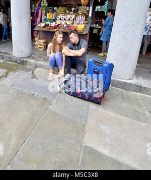 Londra, Inghilterra, Regno Unito. Coppia giovane seduto a terra parlando, Covent Garden Foto Stock
