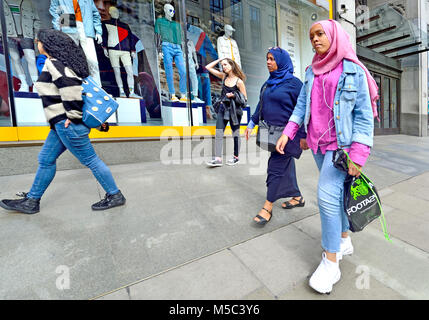 Londra, Inghilterra, Regno Unito. Due donne musulmane camminare davanti a un negozio di abbigliamento Foto Stock