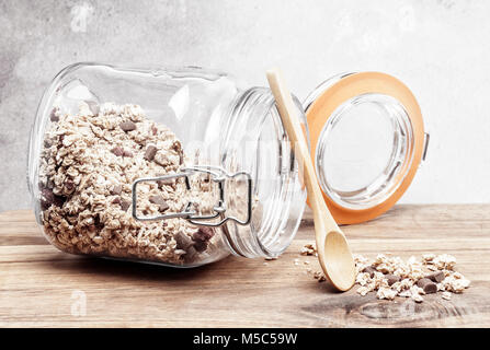 Vasetto di granola con un cucchiaio su un tavolo in legno e sfondo rustico Foto Stock