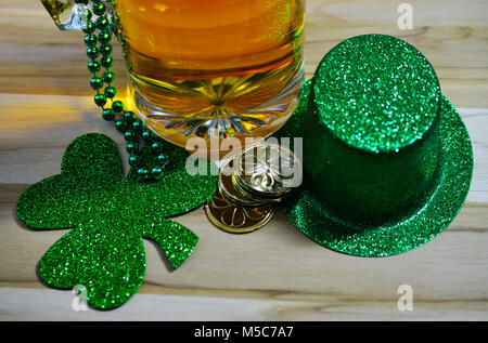 Il giorno di San Patrizio vetro acidato birra Stein riempito con birra, perline verdi, monete d'oro e verde irlandese top hat sulla luce colorato tavolo. Foto Stock