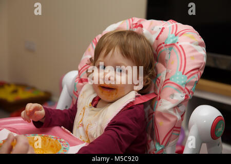 Una femmina di bambino con un confuso faccia dopo aver mangiare spaghetti bolognese Foto Stock