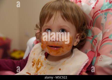 Una femmina di bambino con un confuso faccia dopo aver mangiare spaghetti bolognese Foto Stock