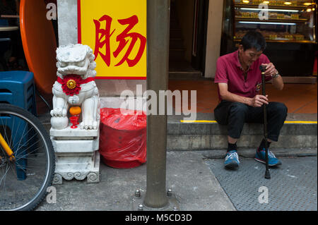 18.01.2018, Singapore, Repubblica di Singapore, in Asia - un uomo si siede sul bordo della strada a Singapore il quartiere Chinatown. Foto Stock