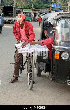 Un giovane uomo su una bicicletta nazionale vende i biglietti della lotteria per un tuk tuk driver, Nuwara Eliya, provincia centrale, Sri Lanka, Sud Asia Foto Stock