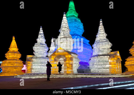 Scene notturne dal Harbin Ice Festival, Heilongjiang, Cina. I visitatori di prendere le fotografie di fronte alcune sculture di ghiaccio. Foto Stock