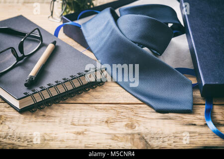 La festa del papà concetto. Cravatta blu al di fuori di un box regalo su una tavola di legno scrivania da ufficio, lo spazio per il testo Foto Stock