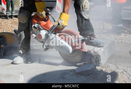 Builder lavoratore con cut-off di alimentazione della macchina utensile di rottura in corrispondenza di calcestruzzo strada sito in costruzione Foto Stock