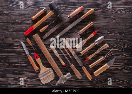 Un assortimento di strumenti di lavoro in legno nero tabella. Foto Stock